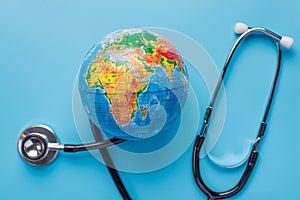 Go green coronavirus outbreak concept. Top above flat lay close up photo of stethoscope around planet isolated on blue background