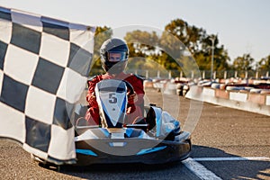 Go-kart driver crossing at finish line moving to checkered racing flag