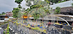 Go-kart games are at the top of the hill surrounded by trees that use blue and yellow tires as a barrier to the playing area.