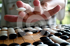 Go player hand holding white piece