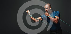 Go! Sportsman working out with resistance band over dark background