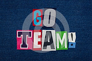 GO TEAM text word collage, multi colored fabric on blue denim, teamwork concept