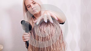 Go to a beauty salon. Professional hairdresser woman dries hair with hair dryer.