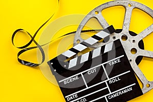 Go to the cinema with film type and clapperboard on yellow background top view