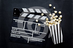 Go to the cinema with popcorn and clapperboard on black background top view