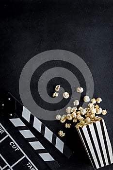 Go to the cinema with popcorn and clapperboard on black background top view mock up
