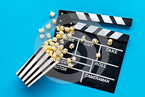 Go to the cinema with popcorn and clapperboard on blue background top view