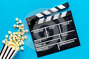 Go to the cinema with popcorn and clapperboard on blue background top view