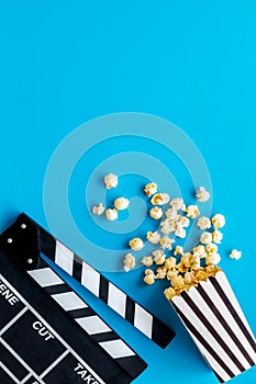 Go to the cinema with popcorn and clapperboard on blue background top view mock up