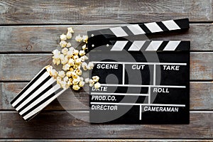 Go to the cinema with popcorn and clapperboard on wooden background top view