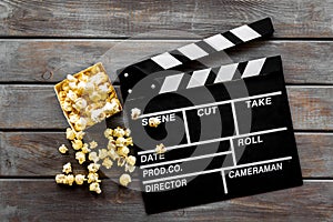 Go to the cinema with popcorn and clapperboard on wooden background top view