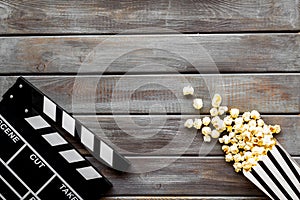 Go to the cinema with popcorn and clapperboard on wooden background top view mock up
