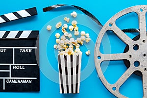 Go to the cinema with popcorn, film type and clapperboard on blue background top view