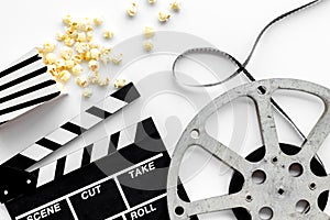 Go to the cinema with popcorn, film type and clapperboard on white background top view