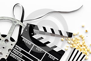 Go to the cinema with popcorn, film type and clapperboard on white background top view