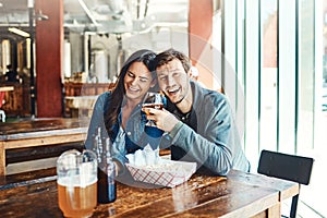 We go together like Friday and happy hour. a happy young man and woman having beers at a bar.