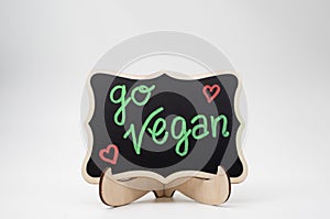 Go vegan, written on a black chalkboard with wooden frame photo