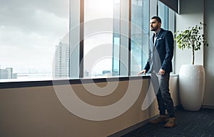 Go after what you want. a young businessman looking thoughtfully out of an office window.