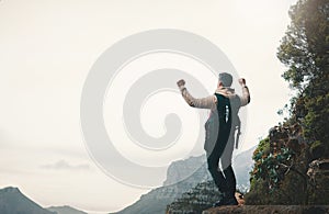 Go where you feel most alive. Rearview shot of a young man standing with his arms outstretched while hiking on a