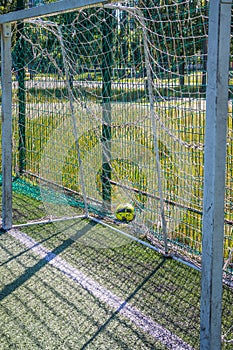 Goal on a football field with artificial green grass near the school. Amateur football field. Sunny summer day