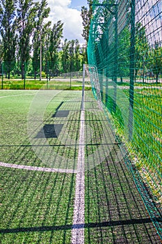 Goal on a football field with artificial green grass near the school. Amateur football field. Sunny summer day