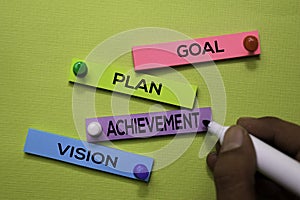 Goal, Plan, Achivement, Vision text on sticky notes isolated on green desk. Mechanism Strategy Concept