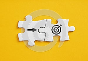 Goal target and arrow symbols connected on jigsaw puzzle pieces