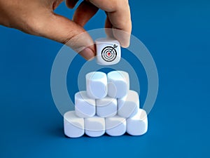 Goal target icon on white blocks holding by hand on business chart on blocks steps on blue background.