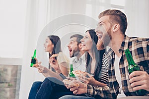 Goal! Very excited youth is having fun by watching football match and drink beer, eat pizza at home indoors