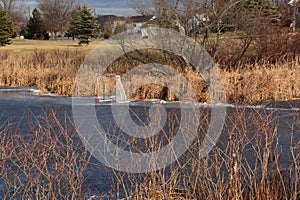 A goalie box stands isolated on the ice of a slough