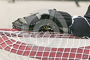 Goalie resting his glove hand on the net between plays