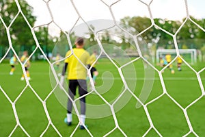 Goalkeeper back view goal post. Young team footballers play soccer background. Youth players soccer on football ground