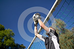 Goalkeeper with ball at football goal on field