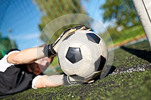 Goalkeeper with ball at football goal on field