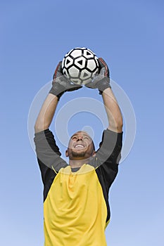 Goalkeeper Catching Soccer Ball Against Blue Sky