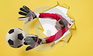 Goalkeeper exits from a hole and tries to tatches the ball. yellow background