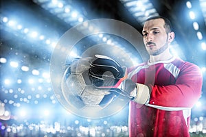 Goalkeeper holds the ball in the stadium during a football game.