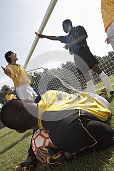 Goalkeeper with soccer ball, referee in background