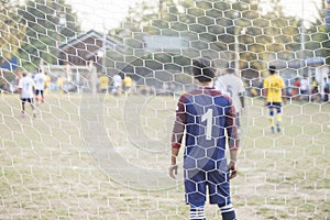 Goalkeeper stands against goal with net and stadium. Football gate net. Behind goal of soccer field