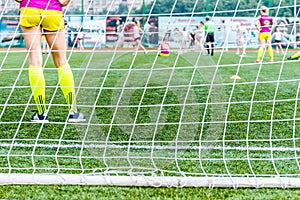 goalkeeper woman stands against goal with net and stadium. female soccer player diving to catch the ball. sporty girl