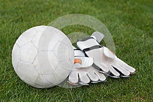 Goalkeeping gloves and football on pitch