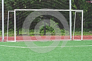 Goalmouth on artificial green playing field, net after white goal