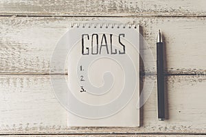 Goals concept. Notebook with goals list on wooden table. Motivation