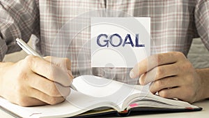 Goals memo written on a notebook with woman hand pen