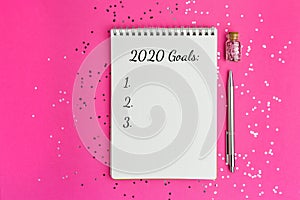 Goals for New Year 2020. Christmas, mockup for your design. notebook and pen on pink background, flat lay style. Silver sparkles