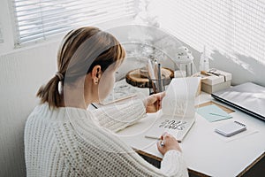 2022 goals, New year resolution. Woman in white sweater writing Text 2022 goals in open notepad on the table. Start new