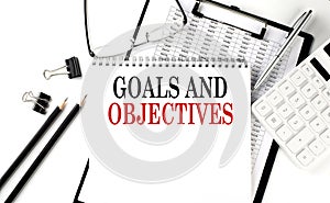 GOALS AND OBJECTIVES word on notepad with clipboard , chart and calculator, business concept