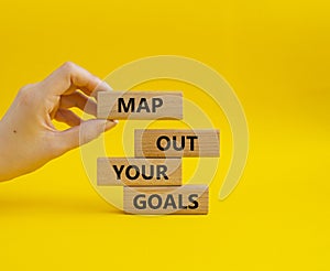 Goals symbol. Wooden blocks with words Map out your goals. Beautiful yellow background. Businessman hand. Business and Map out