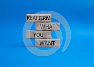 Goals symbol. Wooden blocks with words Reaffirm what you want. Beautiful blue background. Business and Reaffirm what you want