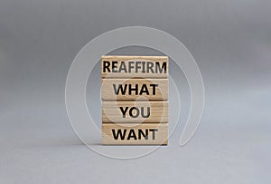 Goals symbol. Wooden blocks with words Reaffirm what you want. Beautiful grey background. Business and Reaffirm what you want